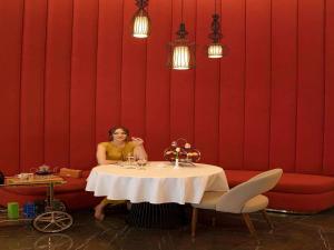 a woman sitting at a table in a restaurant at Pullman Sharjah in Sharjah