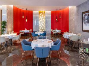 a restaurant with tables and chairs and red curtains at Pullman Sharjah in Sharjah