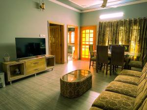 - un salon avec un canapé, une télévision et une table dans l'établissement The Mountain Retreat, Muzaffarabad, à Muzaffarabad