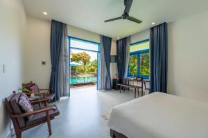 Un dormitorio con cama y escritorio y una habitación con vistas. en Chez Mimosa Rice Farm Hoi An - New address DX18, Thanh Nhut, Cam Thanh en Hoi An
