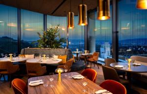 ein Restaurant mit Tischen und Stühlen und großen Fenstern in der Unterkunft Radisson Blu Hotel at Porsche Design Tower Stuttgart in Stuttgart