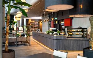 a restaurant with a counter and a restaurant with plants at Radisson Blu Hotel at Porsche Design Tower Stuttgart in Stuttgart
