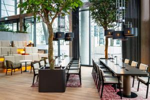 a dining room with tables and chairs and a tree at Radisson Blu Hotel at Porsche Design Tower Stuttgart in Stuttgart