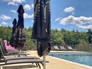 a group of chairs with umbrellas next to a pool at La Grisonne - Chalet 3 in Revest-du-Bion