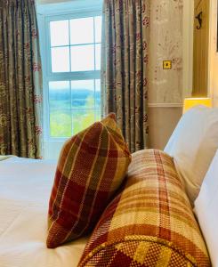 a bed with a plaid pillow and a window at Middle House in Askrigg