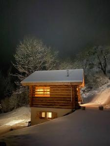 a log cabin in the snow at night at 1000 Borne Caffe Hebergements Insolites in Entremont