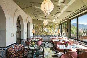 ein Restaurant mit Tischen und Stühlen und großen Fenstern in der Unterkunft Alhambra Palace Hotel in Granada