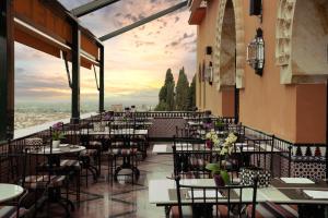 ein Restaurant mit Tischen und Stühlen und Aussicht in der Unterkunft Alhambra Palace Hotel in Granada
