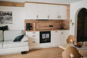 a kitchen with white cabinets and a couch at Gästehaus Sonnenplatzerl in Pfronten