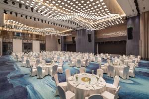 un gran salón de banquetes con mesas y sillas blancas en Wyndham Garden FuKang Downtown en Fukang