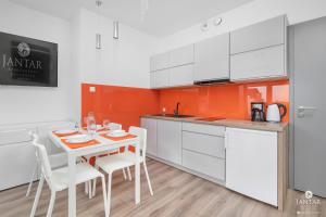 a kitchen with white cabinets and a table and chairs at Jantar Apartamenty - 5 Mórz Sianożęty in Sianozety
