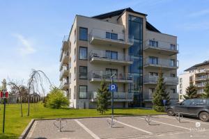 ein Gebäude mit einem Auto auf einem Parkplatz in der Unterkunft Jantar Apartamenty - 5 Mórz Sianożęty in Sianożęty