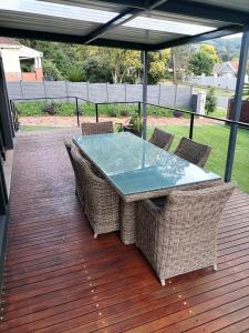 uma mesa de vidro e cadeiras num deque de madeira em One Three Nine On Roberts em Pietermaritzburg