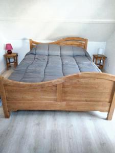 ein Holzbett in einem Schlafzimmer mit 2 Tischen in der Unterkunft Maison de 3 chambres avec jardin clos et wifi a Ecrainville in Écrainville