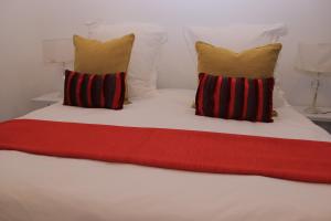 uma cama branca com duas almofadas e um cobertor vermelho em No 2 on Cladon Jadde Apartments em Chartwell