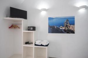 ein Wohnzimmer mit einem TV und einer weißen Wand in der Unterkunft Corrado Caldera Apartments in Fira