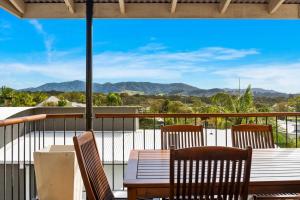 a table and chairs on a balcony with a view of the mountains at Jetty Escape Townhouse in Coffs Harbour