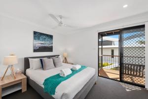 a bedroom with a bed and a balcony at Jetty Escape Townhouse in Coffs Harbour