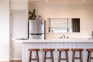 a kitchen with a counter with bar stools and a refrigerator at Stones Throw in Primrose Sands