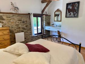 une chambre avec un lit et un mur en pierre dans l'établissement Cottage chez Emilie, à Beaulieu