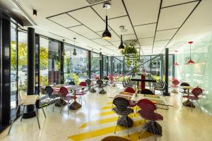 a room with tables and chairs and windows at ibis Styles Bucharest Erbas in Bucharest