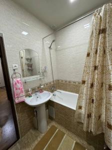 uma casa de banho com um lavatório, uma banheira e um chuveiro em Юнусабад шахристан люкс em Yunusobod