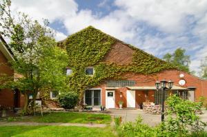 a brick house with ivy growing on it at Ferienwohnung am See in Detern