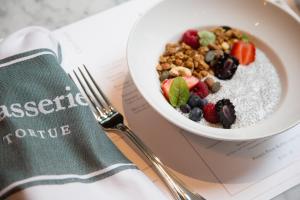 a bowl of cereal and fruit on a table with a napkin at TORTUE Hamburg in Hamburg