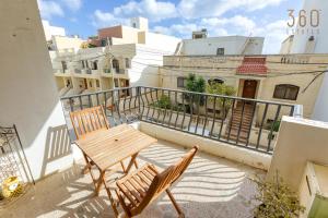 een balkon met een houten tafel en 2 stoelen bij Charming 2BR Apt with Cosy Balcony in Marsascala by 360 Estates in Marsaskala