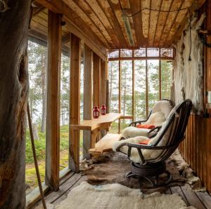 Habitación con silla, mesa y ventanas en VESI - The White Blue Wilderness Lodge en Inari