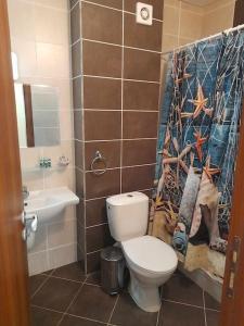 a bathroom with a toilet and a shower curtain at Sunrise apartment 2 bedrooms in Obzor