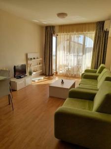 a living room with a green couch and a television at Sunrise apartment 2 bedrooms in Obzor