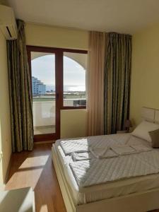 a bedroom with a bed and a large window at Sunrise apartment 2 bedrooms in Obzor