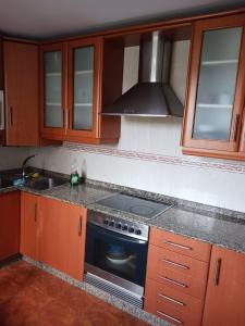 cocina con armarios de madera y horno con fogones en Alojamiento PLAYA DE PANTIN, en A Coruña