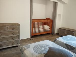 een slaapkamer met 2 bedden, een wieg en een dressoir bij Maison du Troubadour in Balazuc