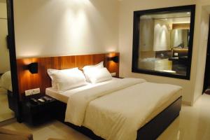 una camera da letto con un grande letto e un grande specchio di Hotel Landmark Ratnagiri a Ratnagiri