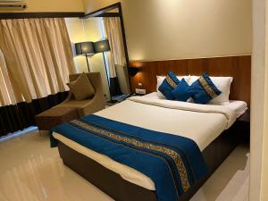 Habitación de hotel con cama y silla en Hotel Landmark Ratnagiri, en Ratnagiri
