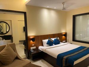 ein Hotelzimmer mit einem Bett und einem Spiegel in der Unterkunft Hotel Landmark Ratnagiri in Ratnagiri