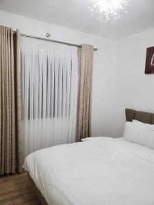 1 dormitorio con cama blanca y lámpara de araña en Executive homes, en Nairobi