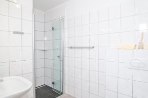 ein weißes Bad mit einer Dusche und einem Waschbecken in der Unterkunft alpsrental Apartments Freja Obertauern in Obertauern