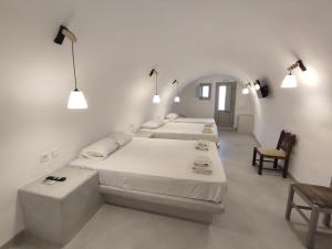 a white room with three beds and a chair at Central Santorini Serenity Rooms in Fira