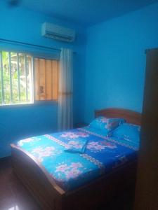 a bedroom with a bed with blue walls and a window at Résidence la Lobe in Kribi