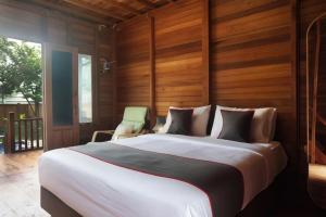 a bedroom with a large white bed with wooden walls at Nemuru Villa Ubud Anyer in Anyer