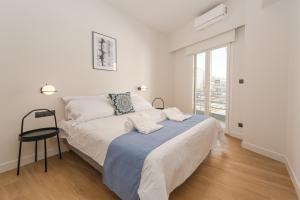 Athens City Chic Apartment-2 bathrooms في أثينا: غرفة نوم بيضاء بسرير وكرسي