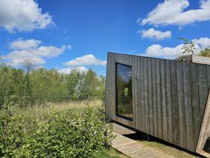 Casa de madera con una gran ventana en un campo en Tiny house De Wylp en Westergeest