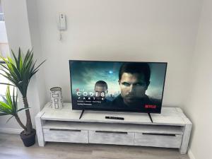 una TV a schermo piatto seduta su un centro di intrattenimento bianco di KozyGuru Redfern Charming 1 Bed Parking NRE012 a Sydney