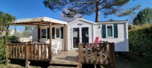 mały biały domek z drewnianym tarasem w obiekcie Mobil home Familial w mieście La Roque-dʼAnthéron