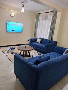 een woonkamer met twee blauwe banken en een tafel bij Angie's staycation 1 br apt Milimani in Kisumu