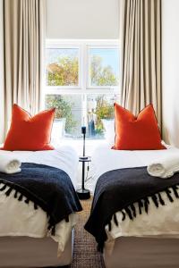 two beds with red pillows in a room with a window at Meliora in Cape Town