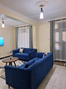 una sala de estar con 2 sofás azules y una mesa. en Angie's staycation 1 br apt Milimani, en Kisumu
